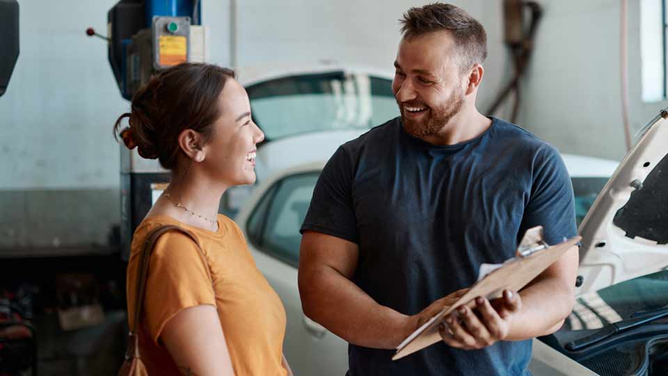 Eine Kundin bekommt in der Werkstatt eine Autobewertung von einem Mitarbeiter erklärt